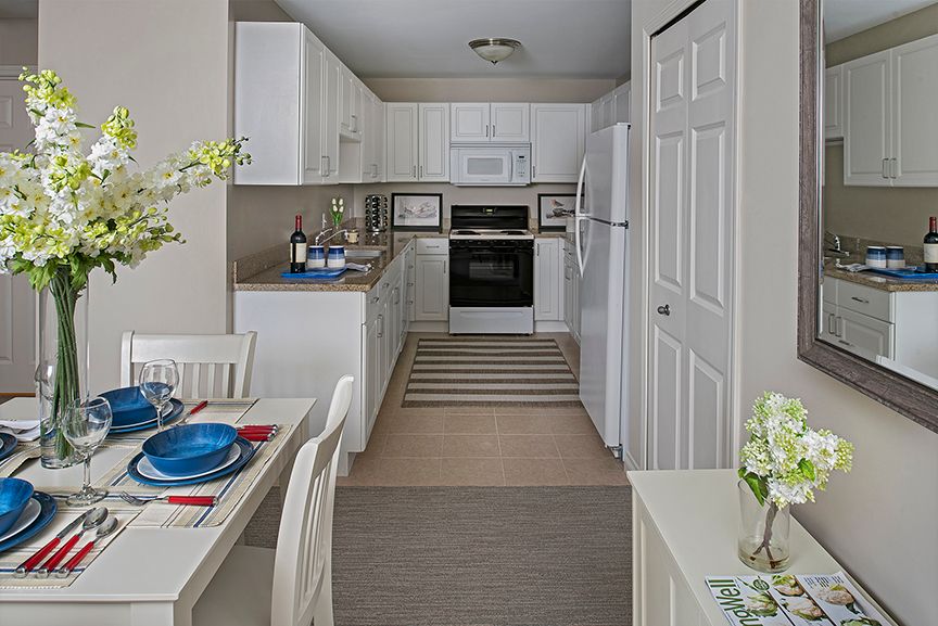 A modern kitchen with white cabinets and a small dining area.