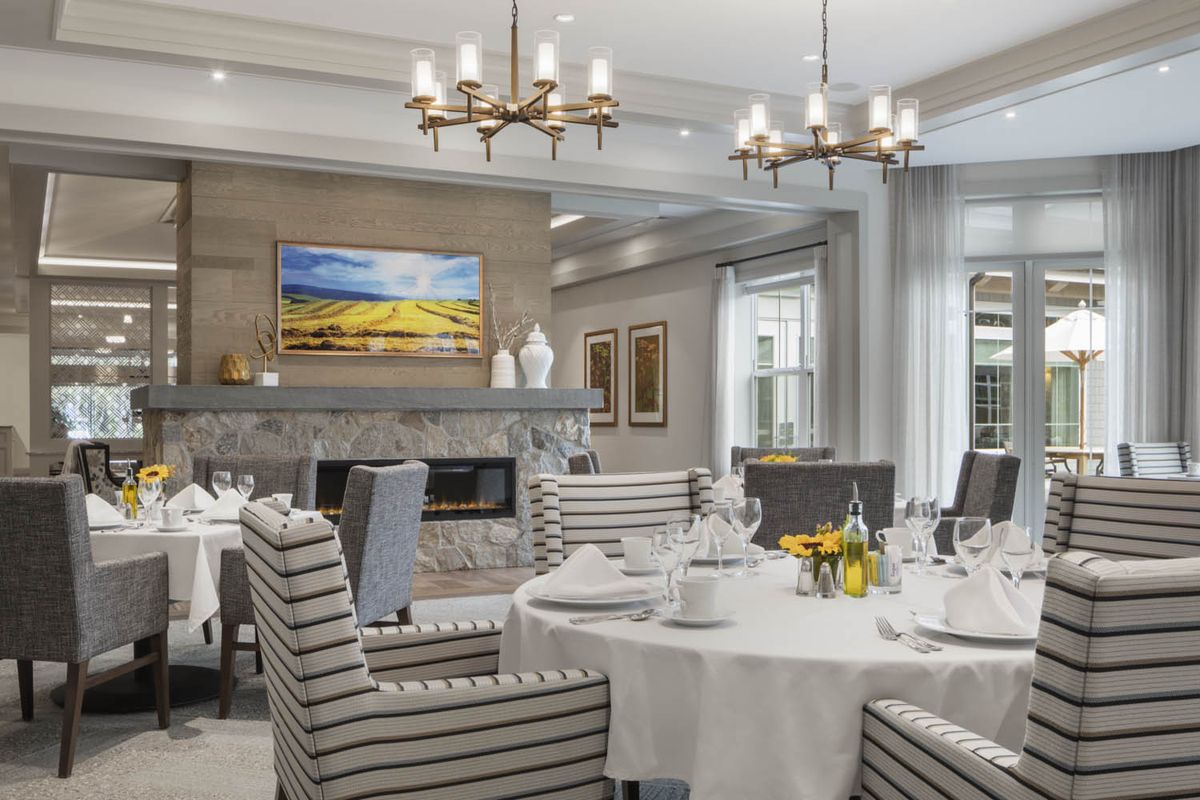 An elegantly designed dining room with chandeliers, a fireplace, and neatly set tables.