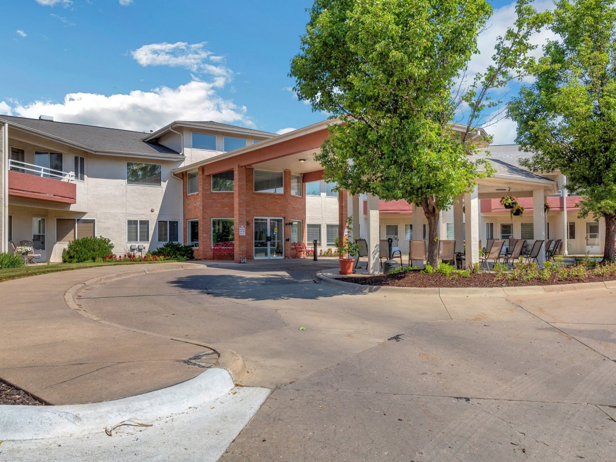 A modern residential building with a landscaped driveway under a clear blue sky.