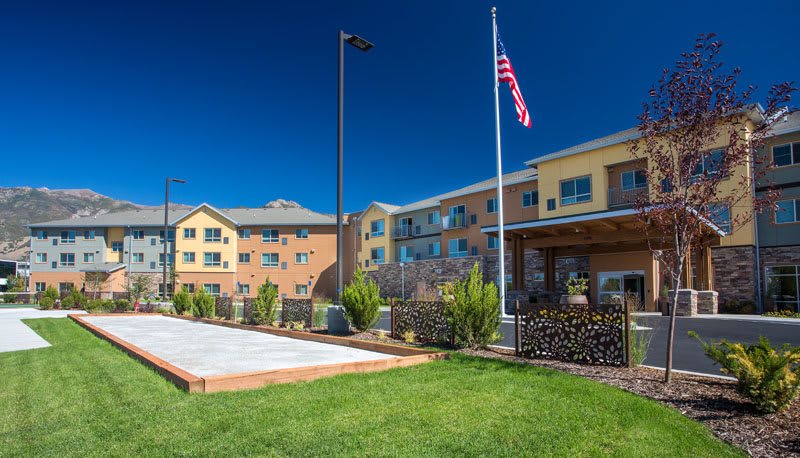 A modern hotel with a lush lawn and an American flag flying outside.