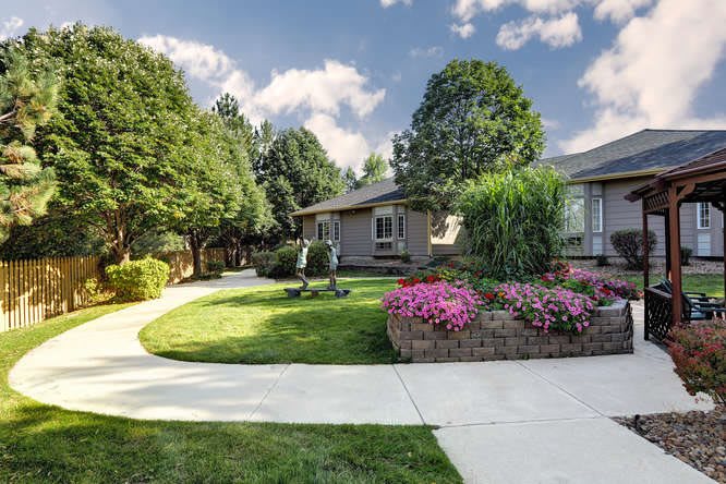 A charming house surrounded by a well-maintained garden with a winding pathway and vibrant flowers.