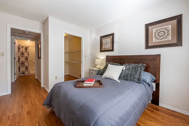A cozy bedroom with a neatly made bed, wooden floor, and decorative wall art.