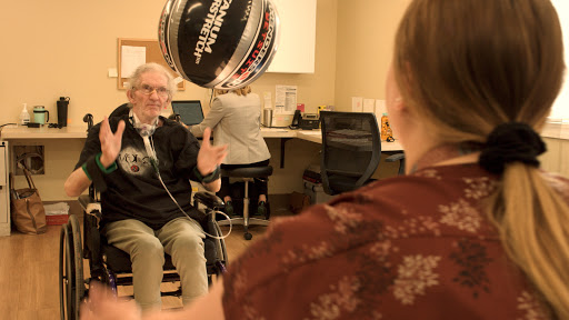 An elderly person engages in a therapeutic activity with a caregiver, highlighting the importance of social interaction in rehabilitation.