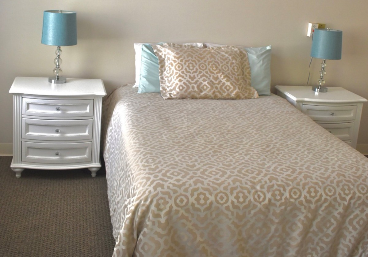 A neatly arranged bedroom with a bed, two nightstands, and matching lamps.