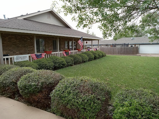 A well-maintained front yard featuring lush green grass and decorative American flags.