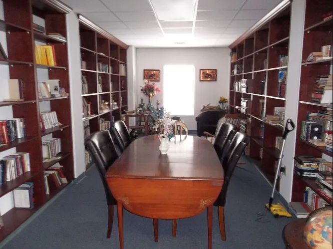 A meeting table surrounded by chairs in a room lined with bookshelves.