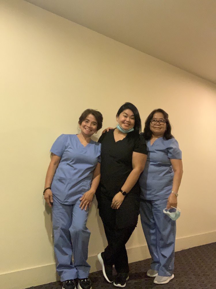 A group of healthcare professionals wearing scrubs, smiling and posing together.