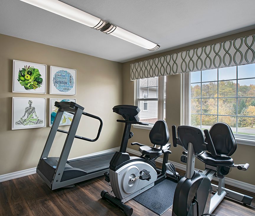 A well-lit indoor gym with a treadmill and stationary bikes.
