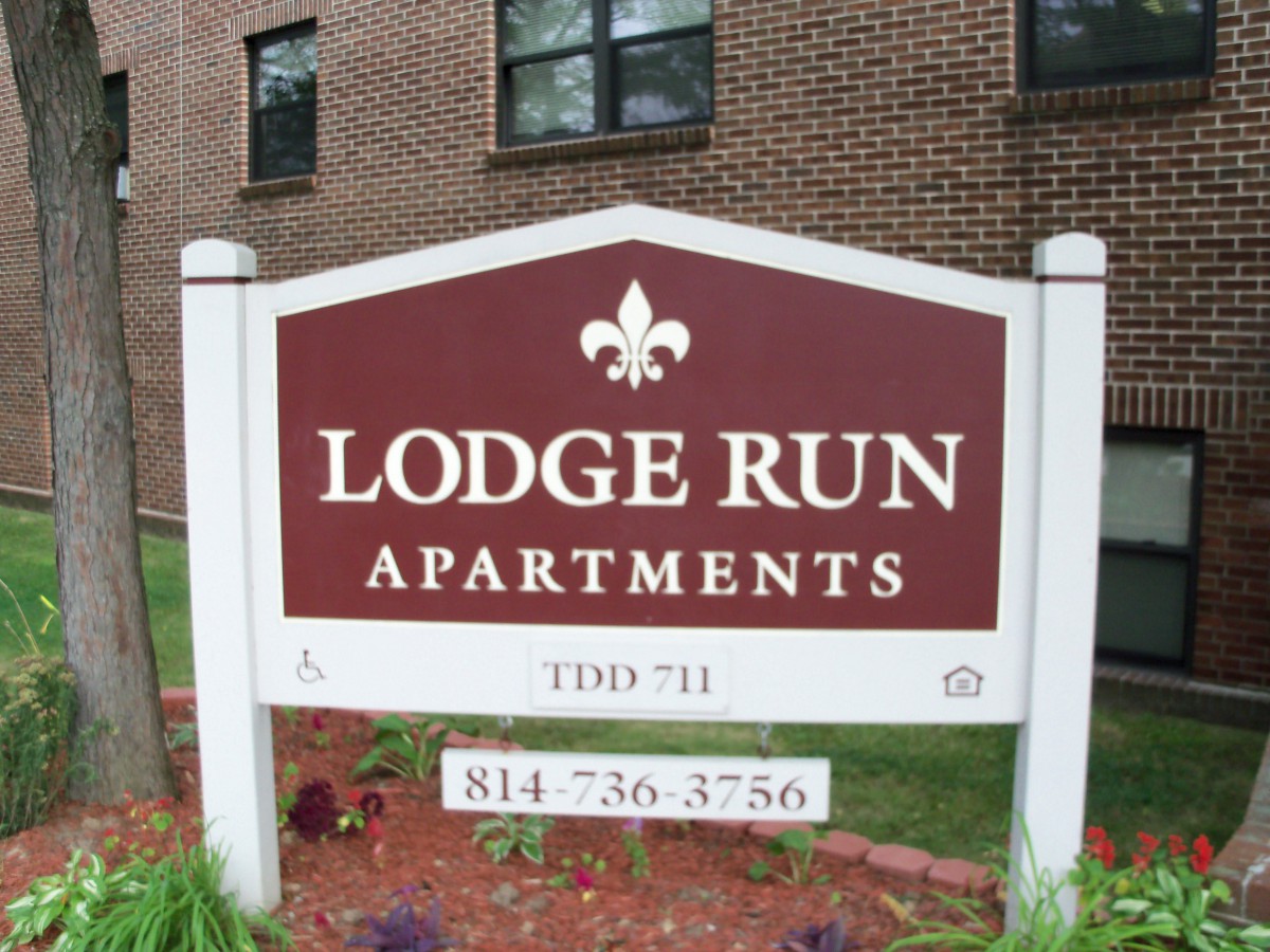 Sign for Lodge Run Apartments in front of a brick building.