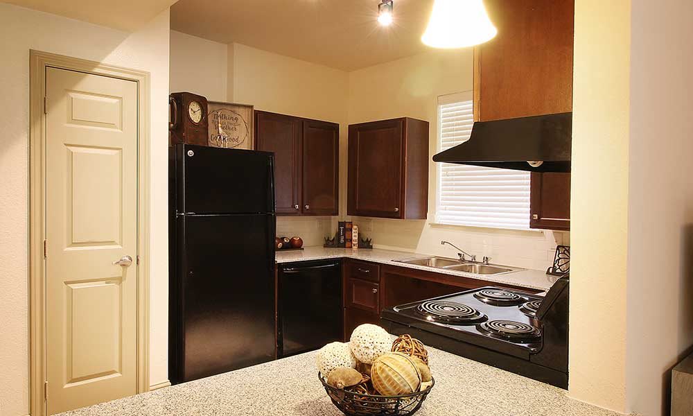A modern kitchen with dark wood cabinets, a black refrigerator, and an oven.
