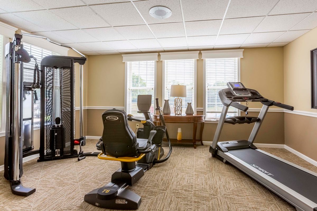 A small gym room featuring a treadmill, stationary bike, and other exercise equipment.