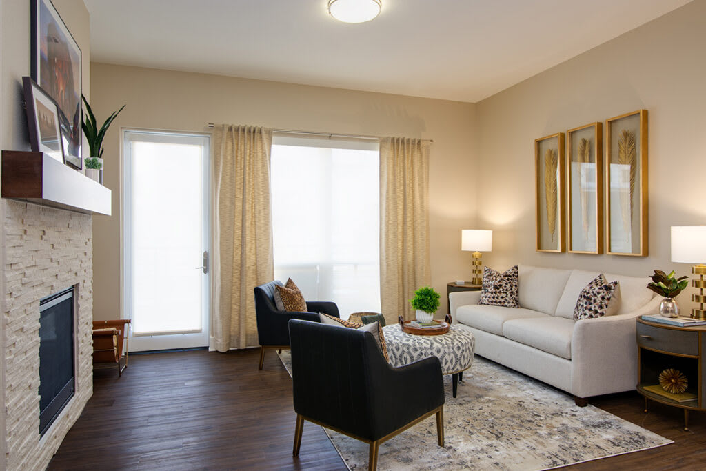 A cozy living room with a sofa, armchairs, a coffee table, and a lamp, featuring neutral tones and soft lighting.