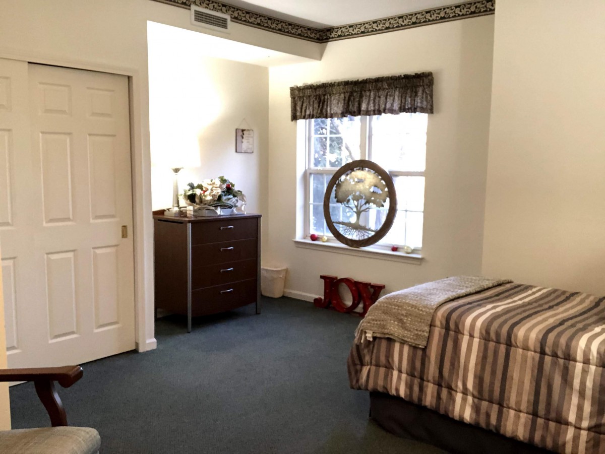 A cozy bedroom with a bed, dresser, and window.