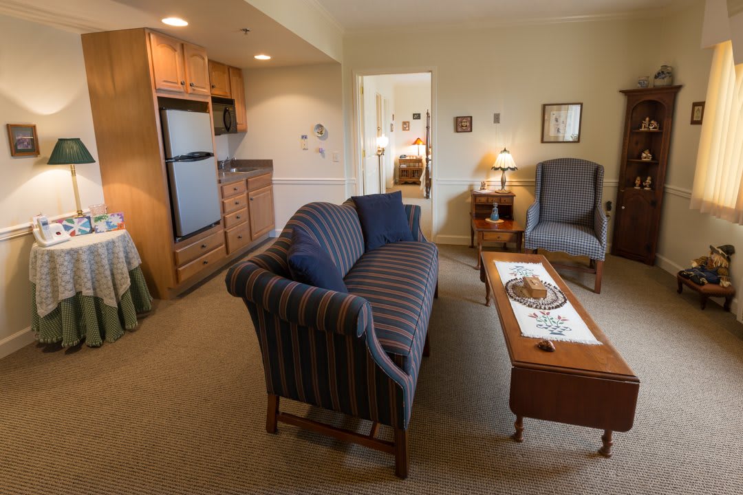 A cozy apartment living room with a sofa, coffee table, and kitchenette.