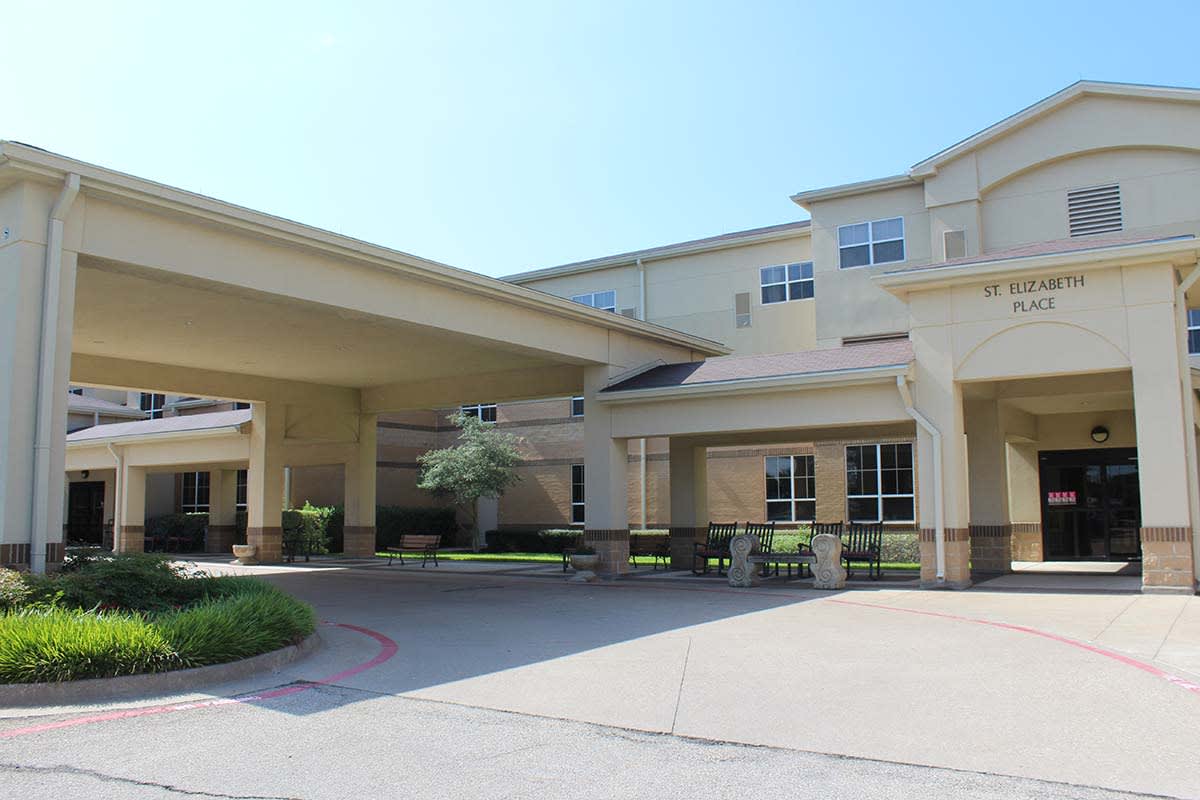 A large building with a covered entrance and driveway, photographed during the day.