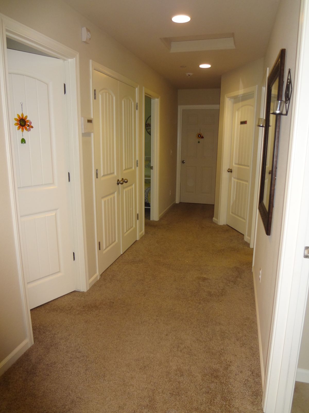 A carpeted residential hallway with multiple doors on both sides.