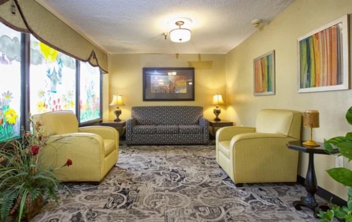 A cozy living room with yellow armchairs, a patterned sofa, and decorative lamps.
