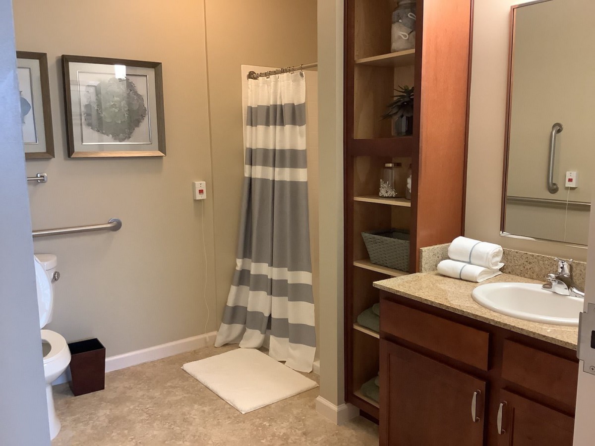 A well-organized bathroom featuring a striped shower curtain, sink with countertop, and storage shelves.