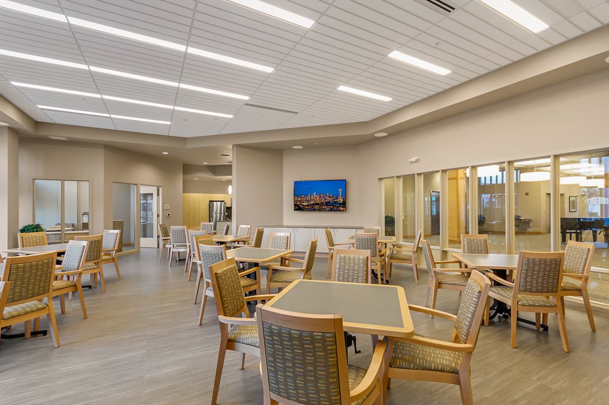 A modern waiting area featuring tables and chairs arranged neatly under bright lighting.