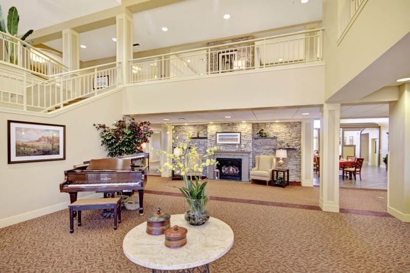 A spacious and elegantly decorated lobby featuring a piano, fireplace, and comfortable seating.
