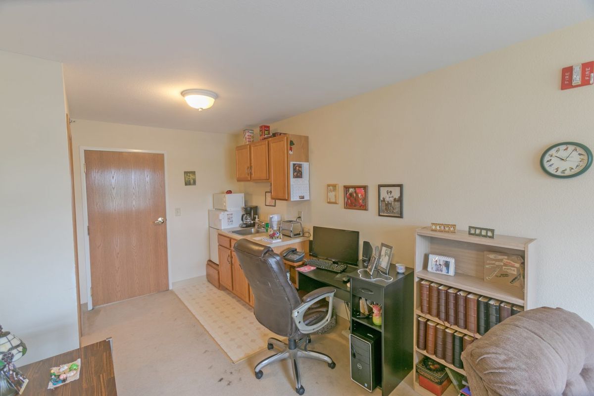 A cozy home office setup with a desk, computer, and bookshelf filled with books.