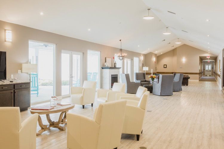 A spacious and modern living room featuring comfortable seating and large windows, allowing ample natural light.