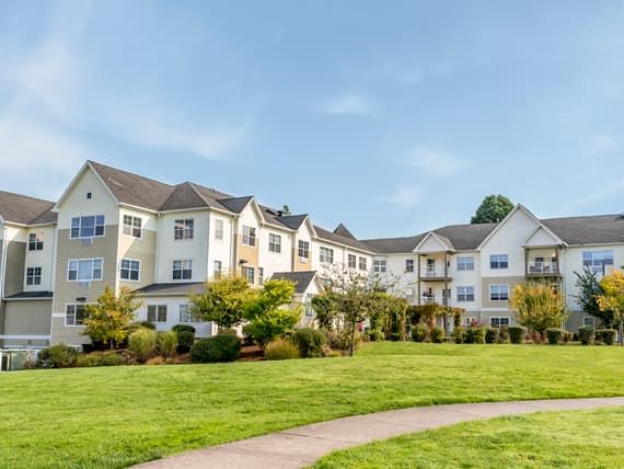 A residential apartment building with a well-maintained lawn and pathway.