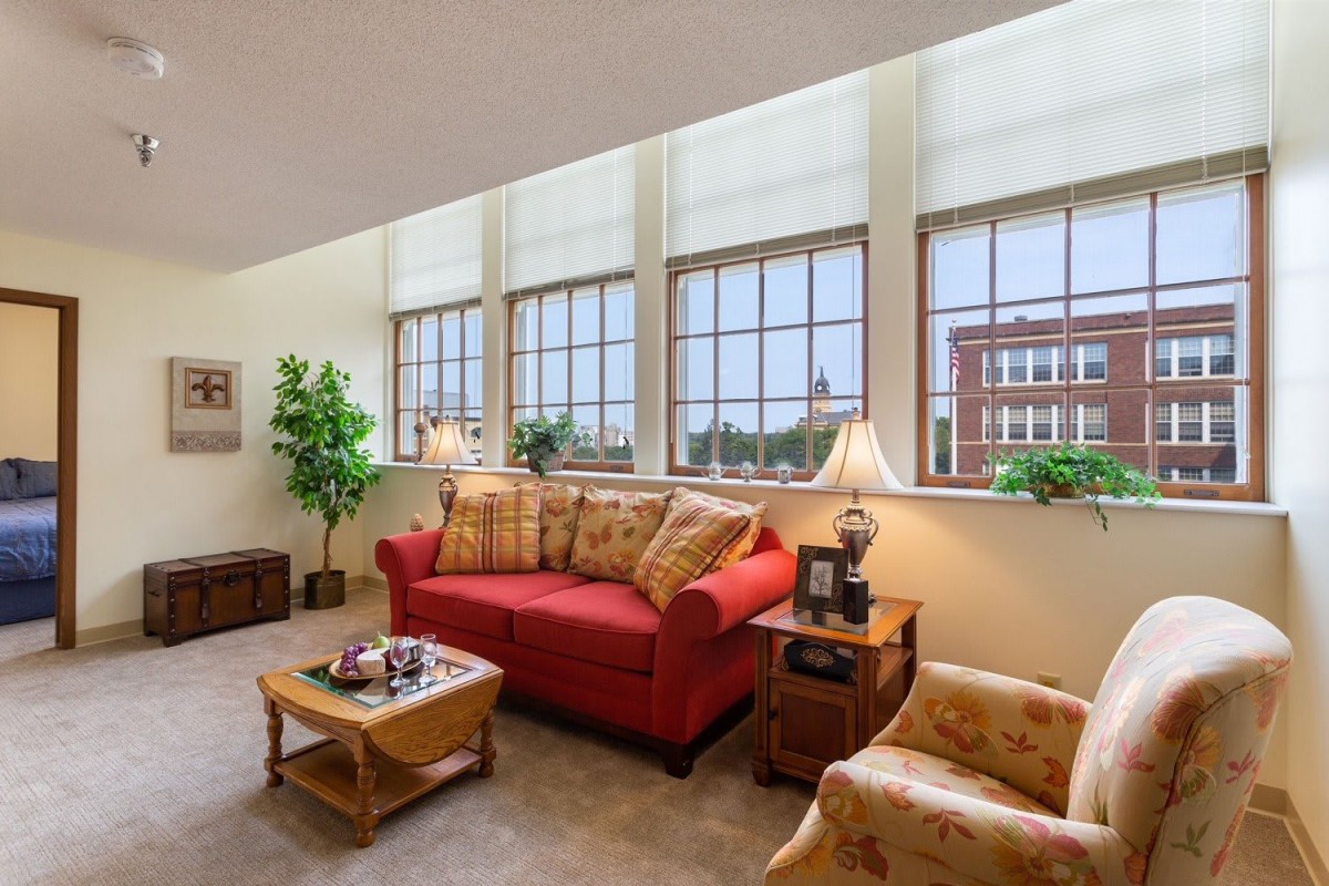 A cozy living room featuring a red sofa, large windows, and elegant decor.
