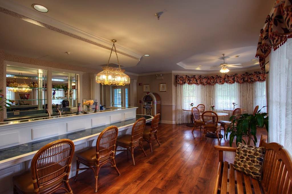 An elegant dining room with a bar counter, featuring wooden flooring and a chandelier.