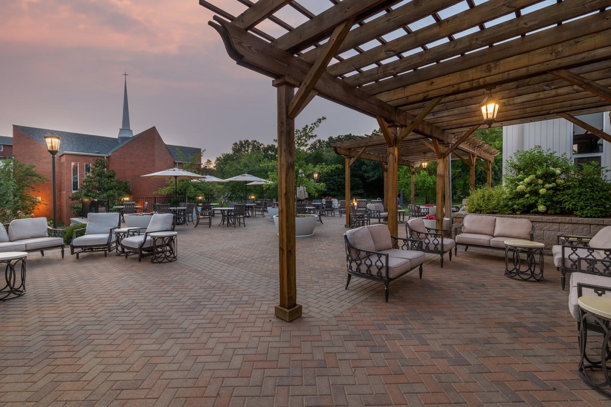 An inviting outdoor patio with comfortable seating and a pergola at sunset.