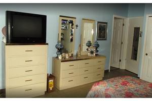 A bedroom with a dresser, mirrors, and a television.