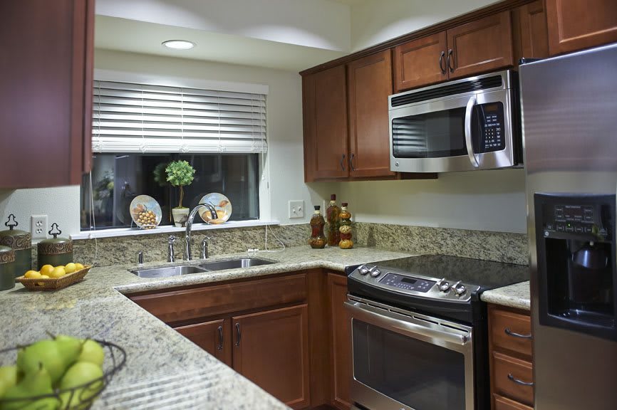 A modern kitchen featuring granite countertops, stainless steel appliances, and wooden cabinets.