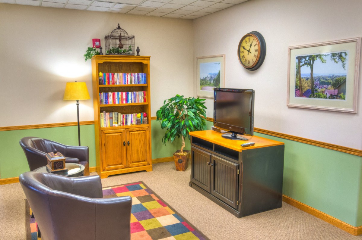 A cozy waiting room with a television, bookshelf, and comfortable seating.