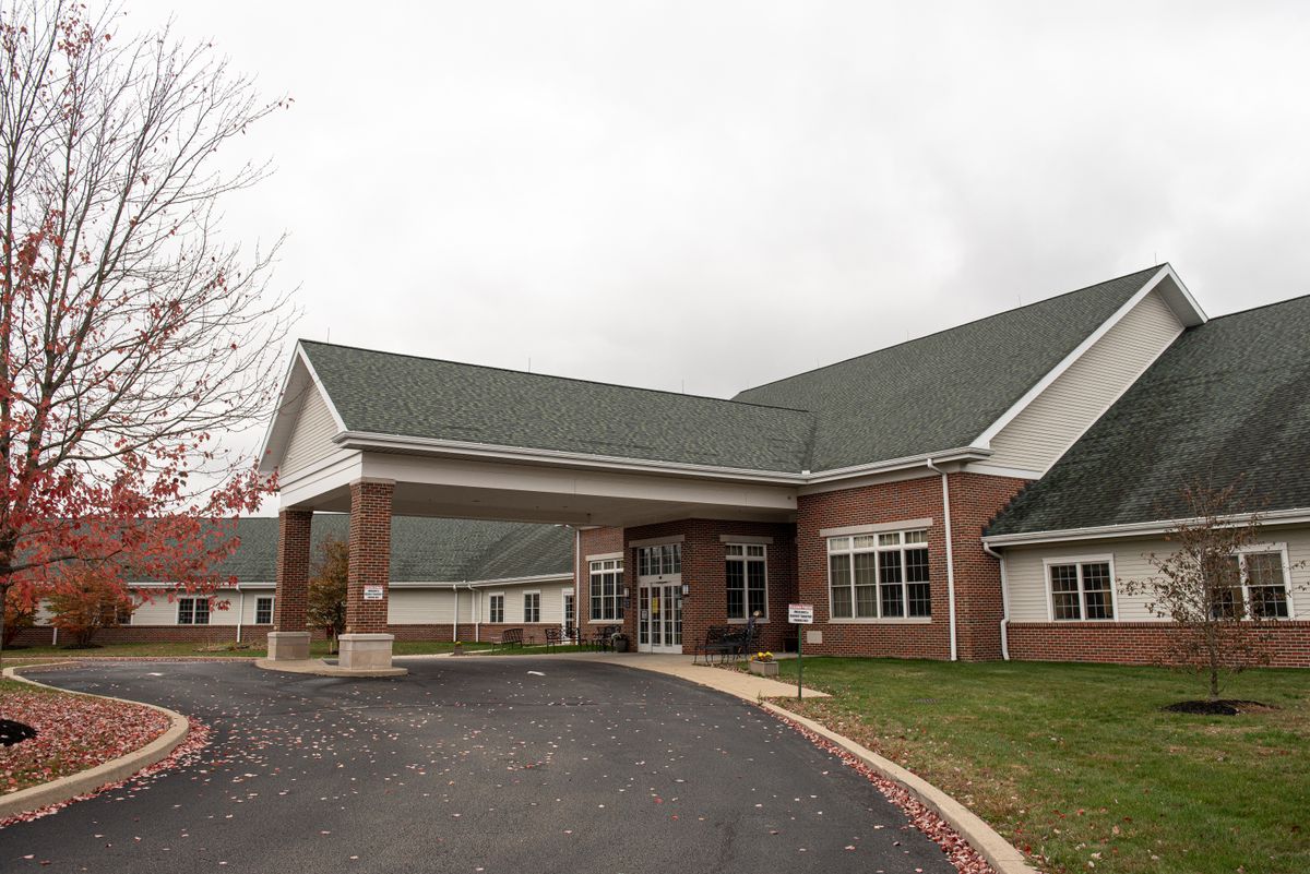 A brick building with a green roof and a driveway leading to the entrance on an overcast day.