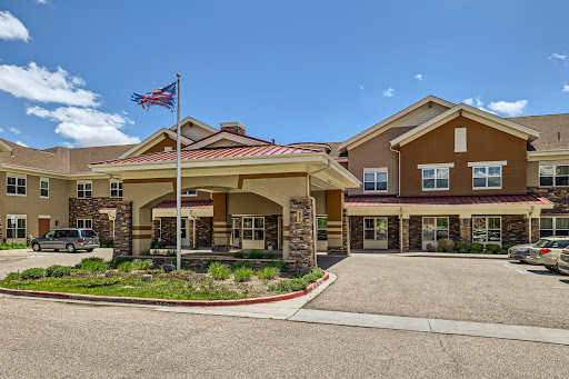 A welcoming hotel entrance with an American flag waving in front under a clear blue sky.