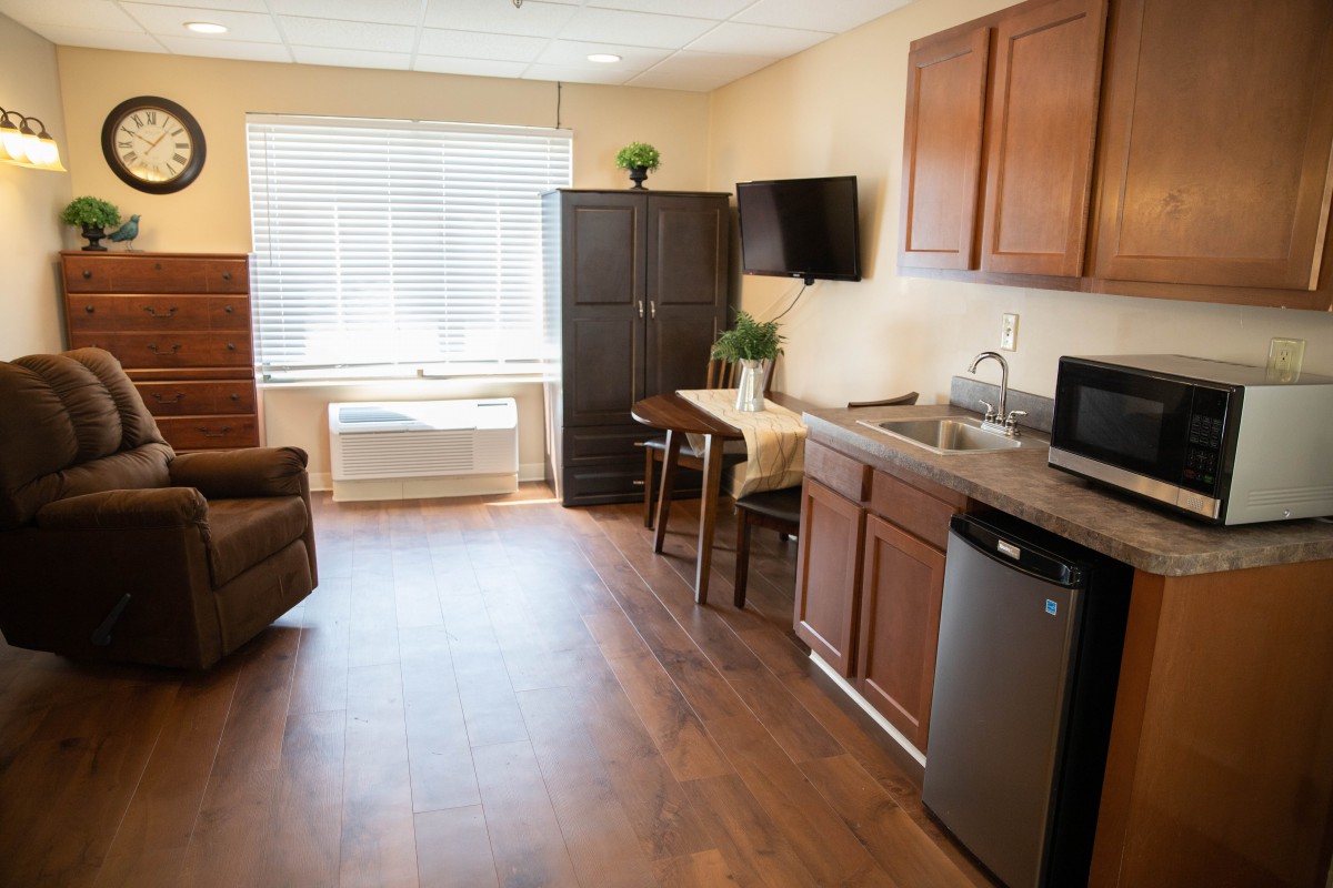 A modern studio apartment with a kitchenette, dining table, and comfortable seating area.