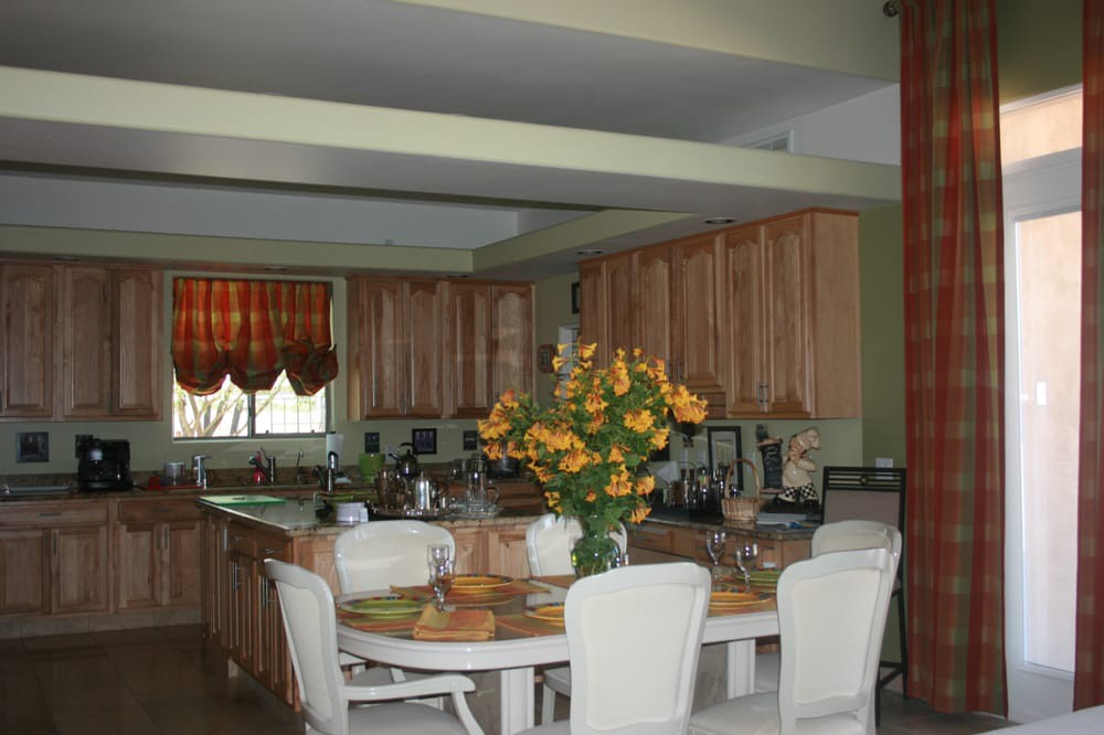 A cozy kitchen and dining area featuring a table with chairs, decorated with a vase of flowers.