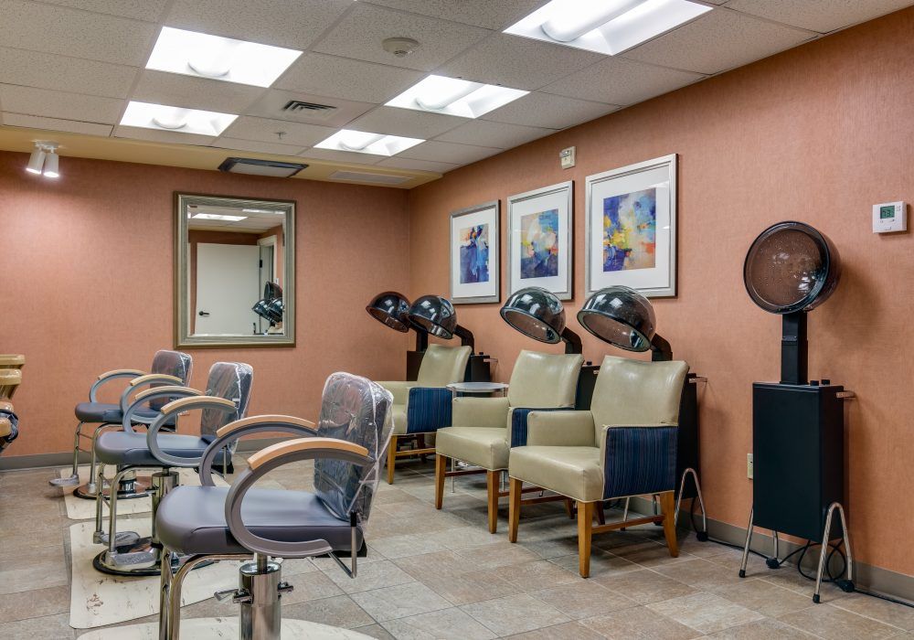 A cozy hair salon interior featuring chairs, hair dryers, mirrors, and wall art.