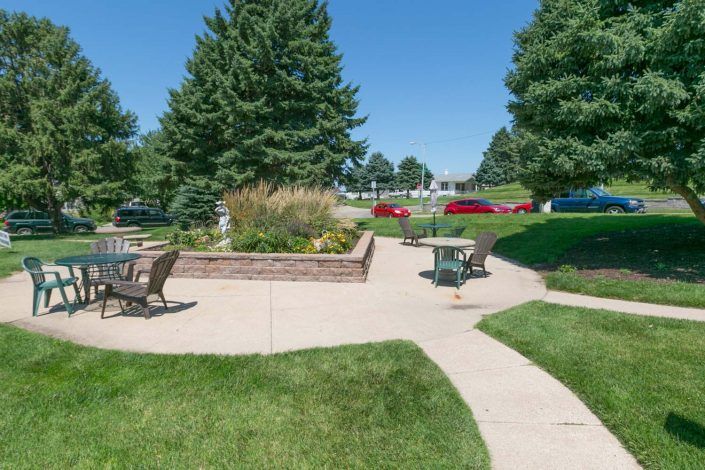 A serene outdoor area with patio furniture, surrounded by trees and a well-maintained lawn.