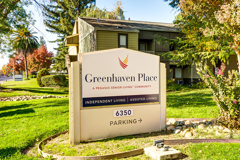 A sign for Greenhaven Place, a senior living community, located in a landscaped outdoor setting.