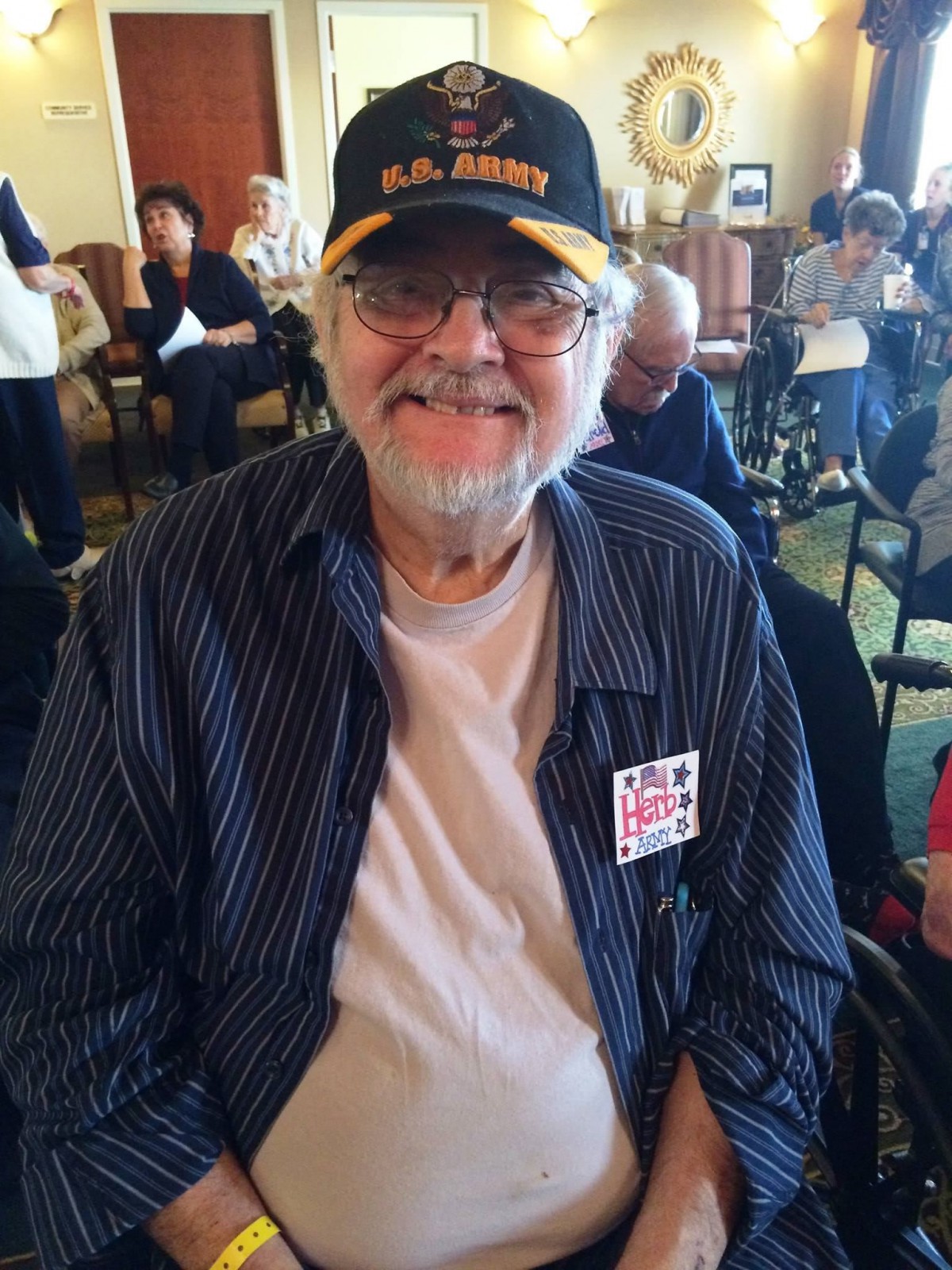 A man wearing a hat and glasses, smiling indoors.