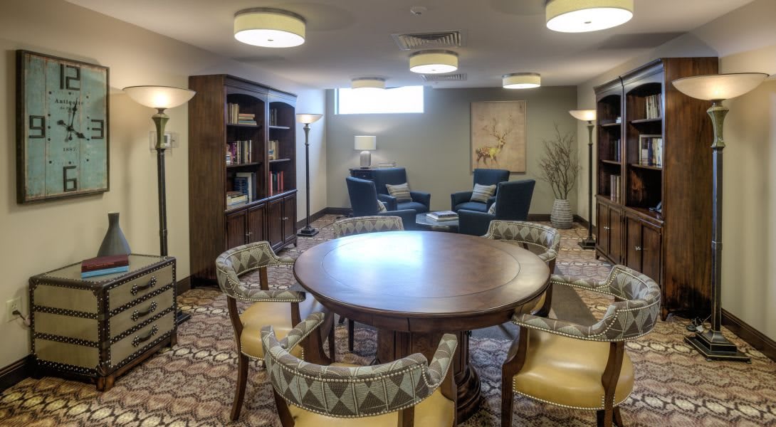 A cozy lounge area featuring a round table with chairs, bookshelves, and comfortable seating.