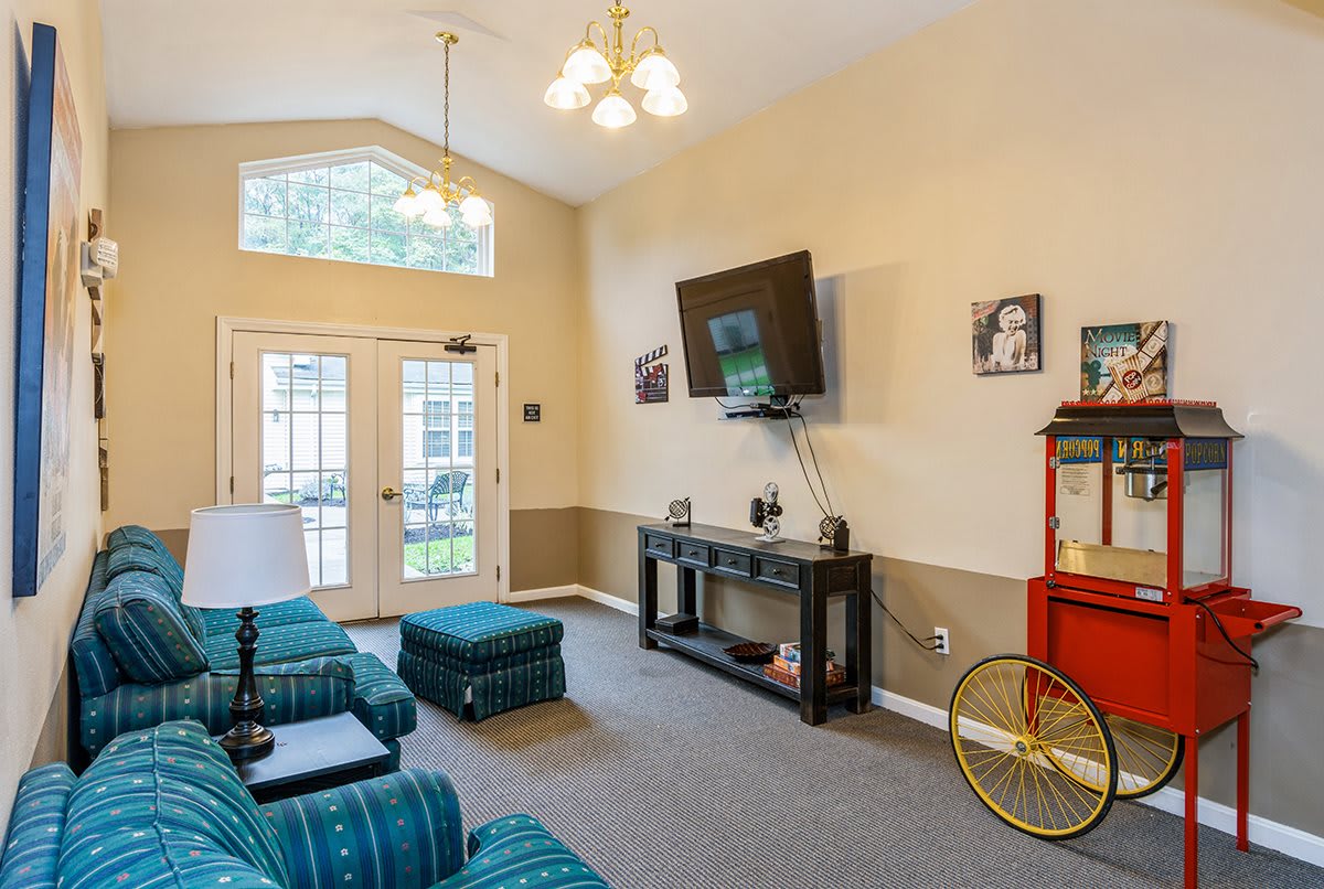 A cozy living room with a wall-mounted TV, comfortable seating, and a popcorn machine.