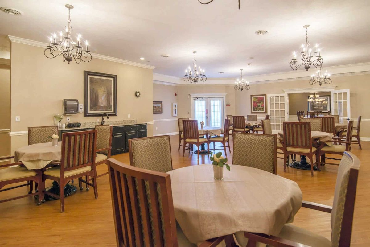 A well-lit dining room with wooden furniture and elegant chandeliers.