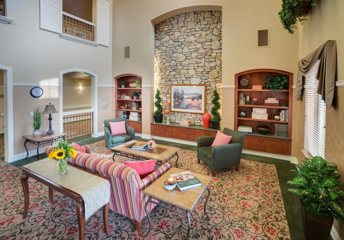 A cozy and well-decorated living room with comfortable seating, bookshelves, and a stone fireplace accent.