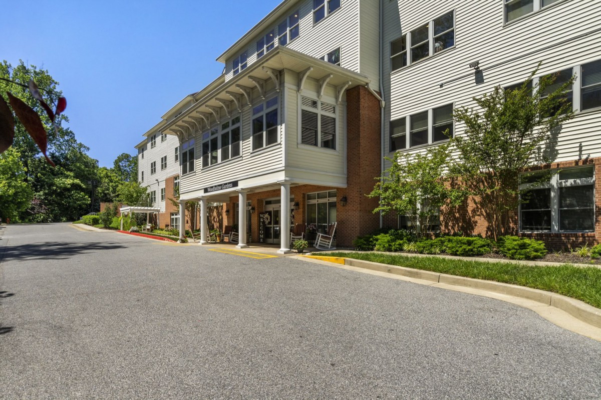 Front view of a modern building with a driveway and landscaped surroundings.