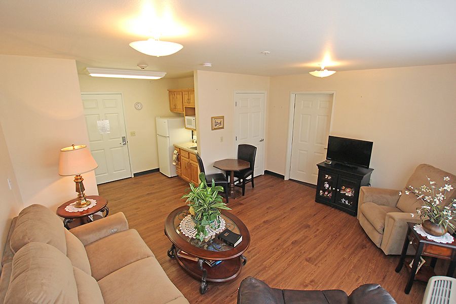 A cozy apartment living room featuring sofas, a coffee table, television, and wooden flooring.
