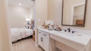 A cozy bedroom with a connected vanity area, featuring soft lighting and elegant decor.