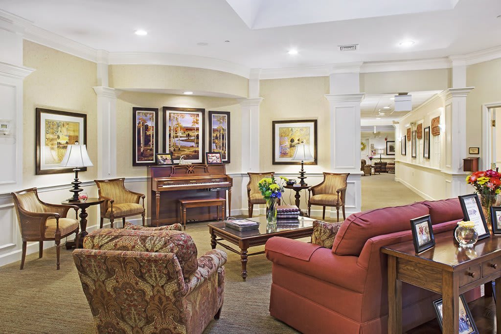 A cozy living room with comfortable seating and elegant decor, featuring a piano and framed artwork.