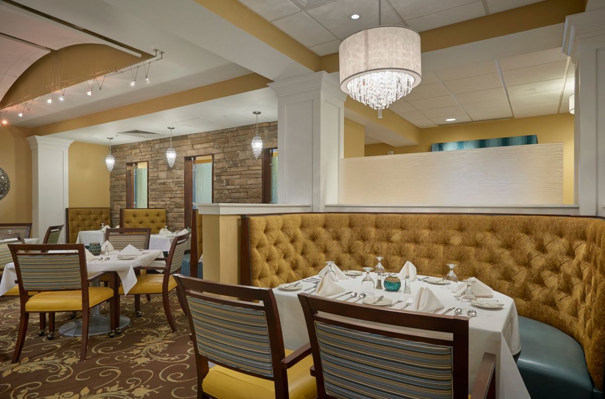 An elegantly designed restaurant interior with neatly arranged dining tables and plush seating.